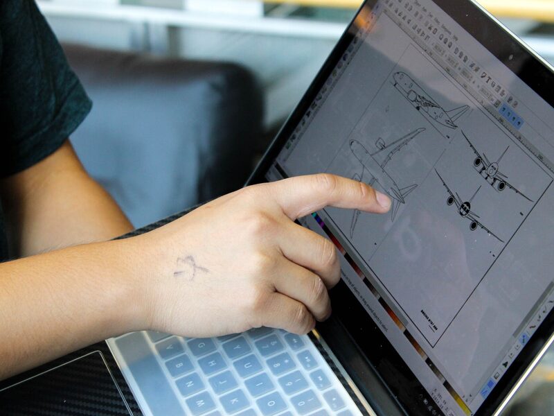 Two students pointing at a sketch on a laptop